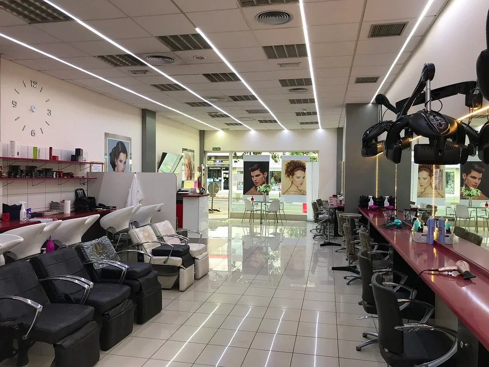 Una peluquería con muchas sillas y un reloj en la pared.