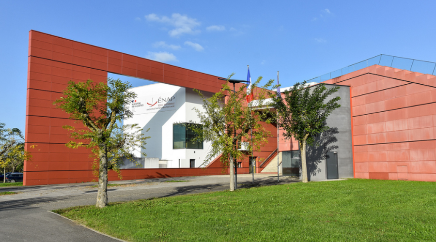 Bâtiment moderne avec des panneaux rouges, un centre blanc et des palmiers sous un ciel bleu