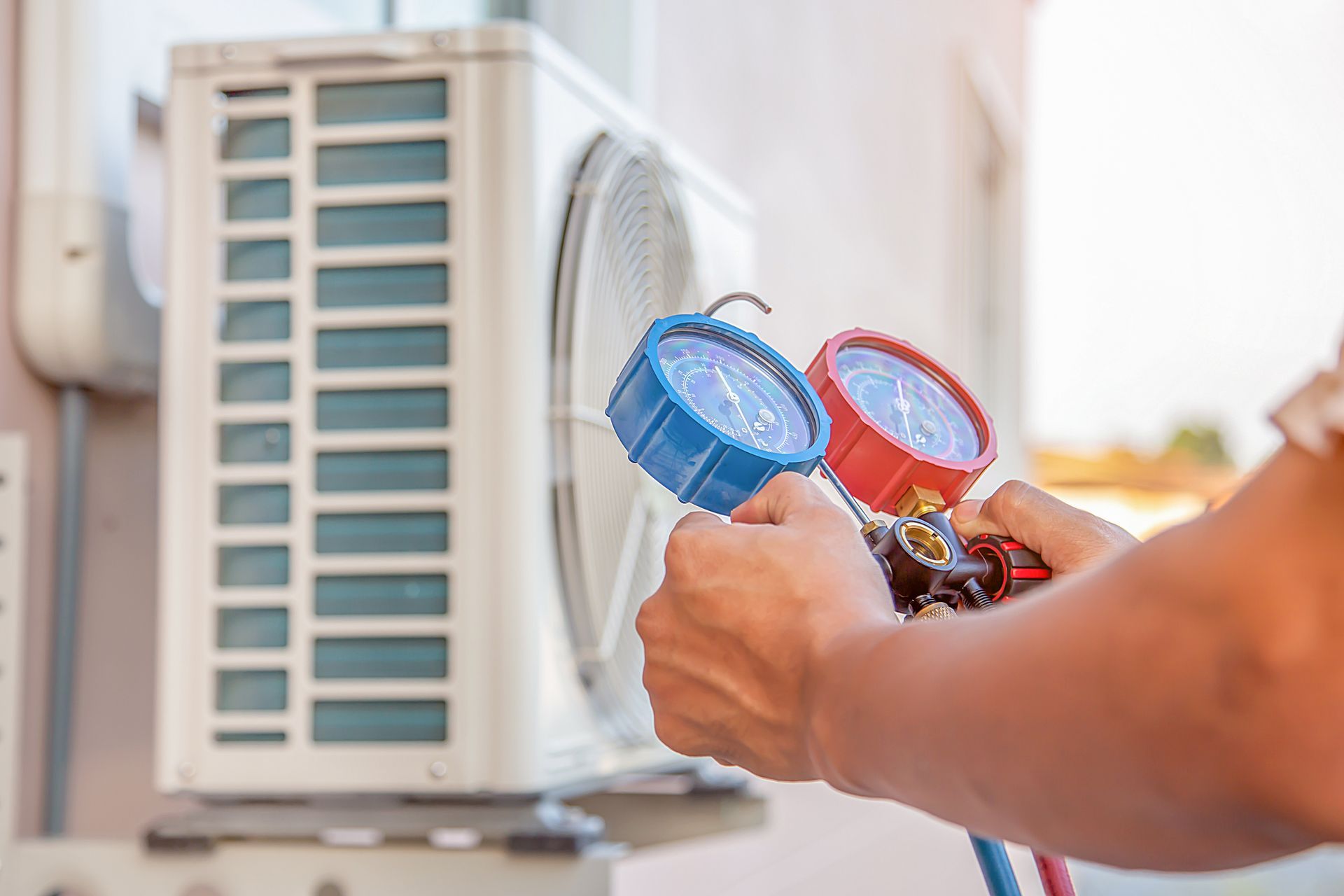 Technicien tenant des manomètres lors de la maintenance d'une unité de climatisation