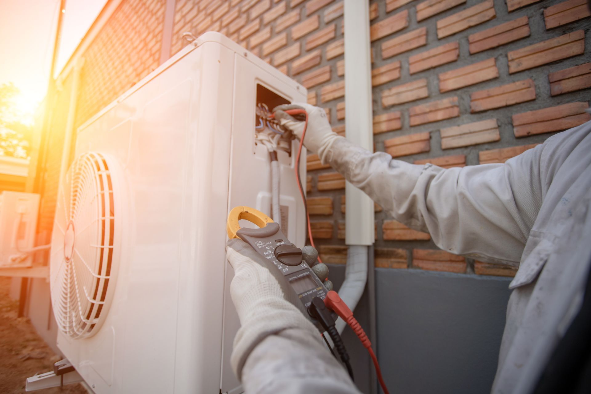 Technicien vérifiant une unité de climatisation avec un multimètre