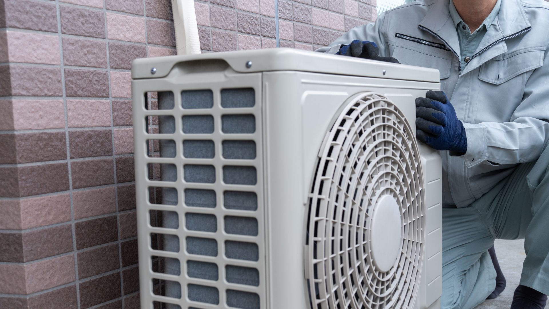 Technicien inspectant une unité extérieure de climatisation.