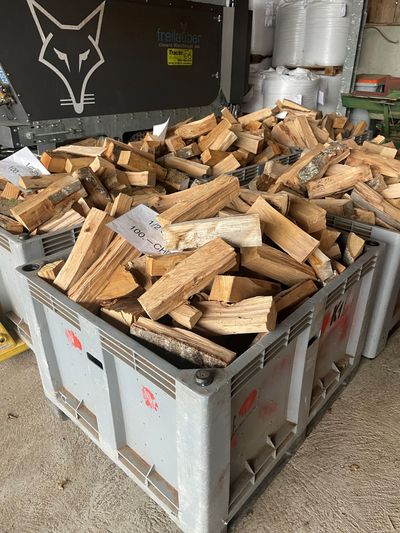Grand conteneur métallique rempli de déchets de bois de chauffage empilés dans une zone de stockage industrielle