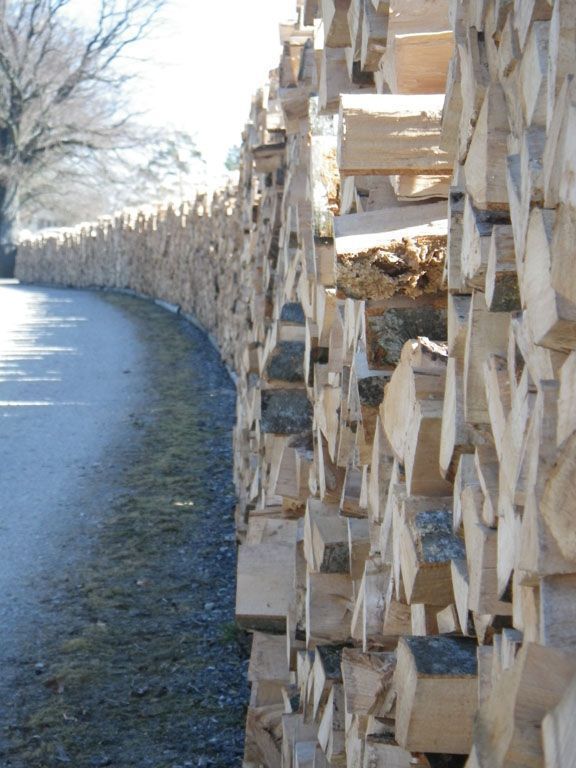 Clôture incurvée de bûches empilées le long d'un chemin enneigé par une journée d'hiver
