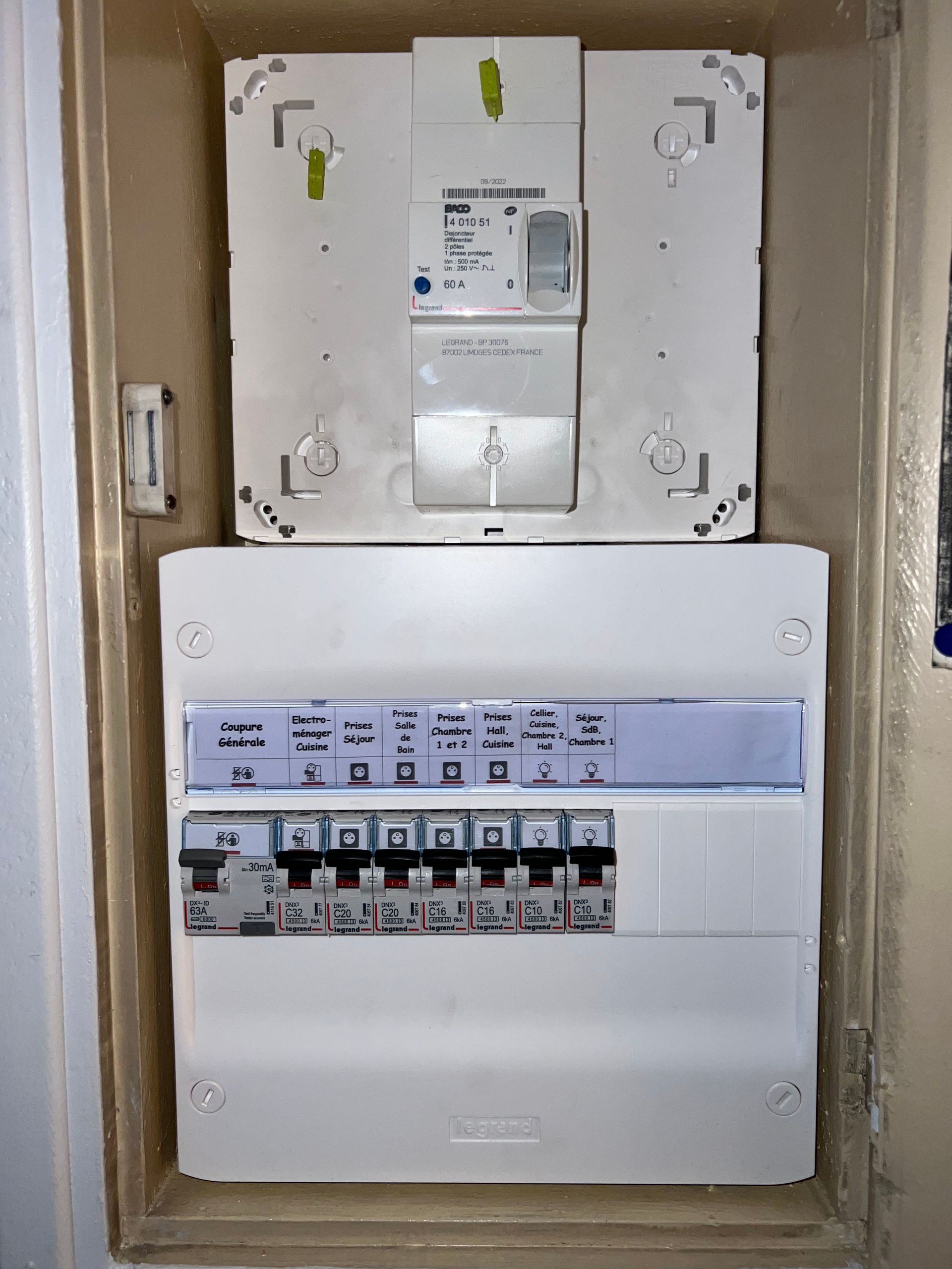 Tableau électrique avec interrupteurs dans un boîtier mural blanc, vu ouvert à l'intérieur d'un placard technique.