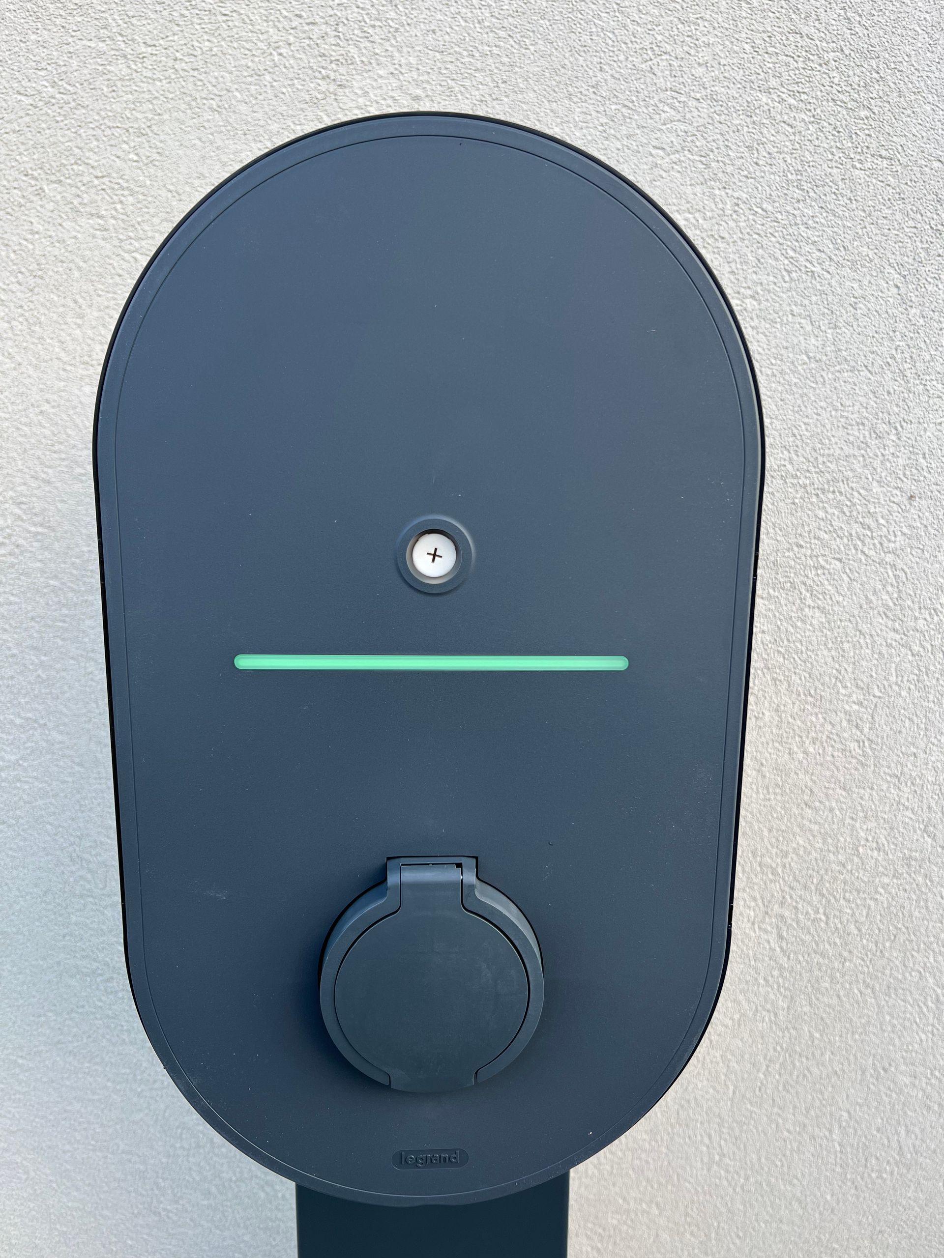 Borne de recharge électrique avec une petite lumière, une ligne indicatrice verte et un bouton rond.