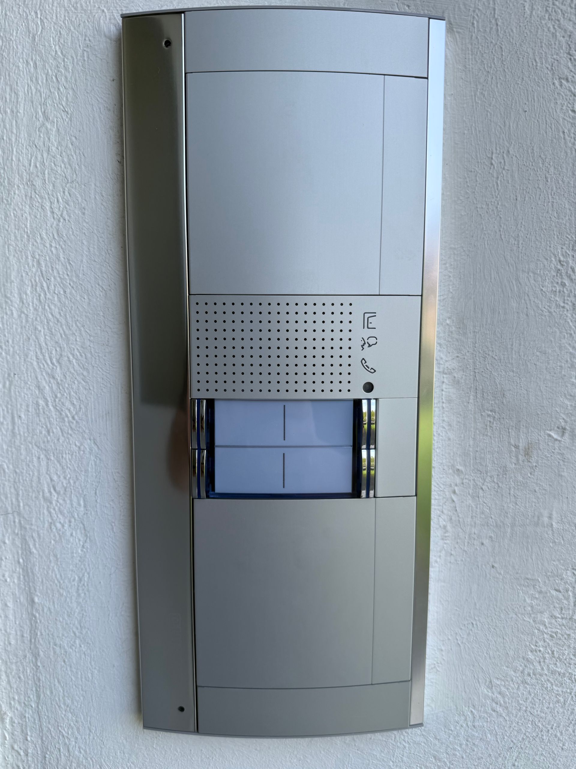 Panneau d'interphone mural moderne avec grille de haut-parleur et écran central dans un couloir