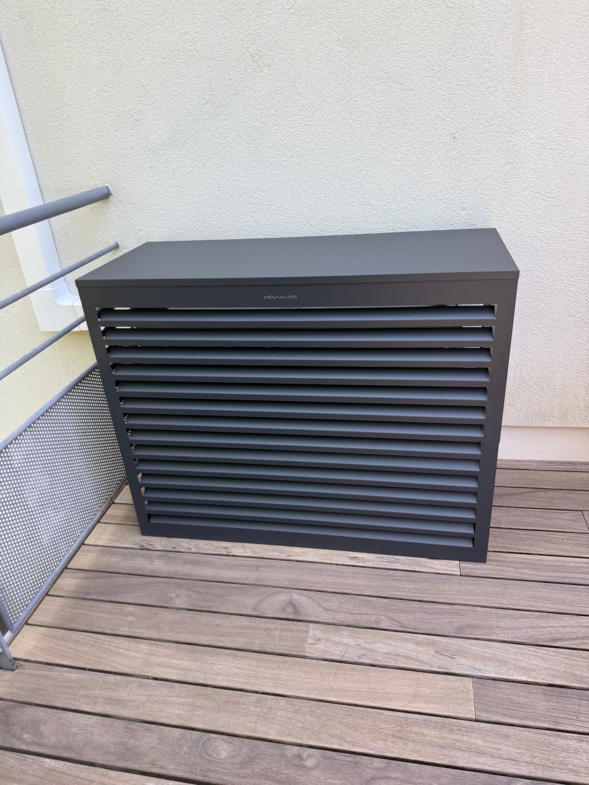 Armoire de rangement extérieure à lattes noires contre un mur en stuc sur une terrasse en bois