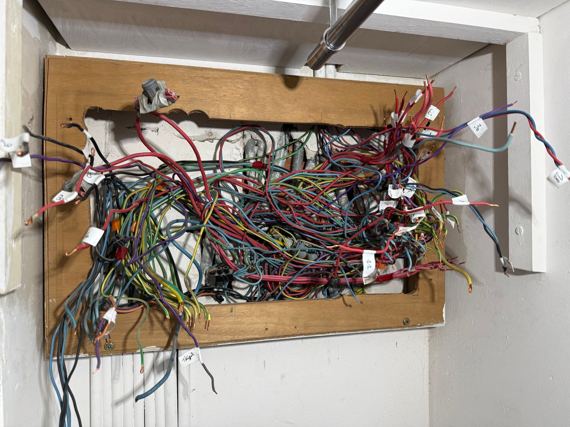 Un enchevêtrement de fils multicolores fixé sur une planche de bois dans une ouverture murale