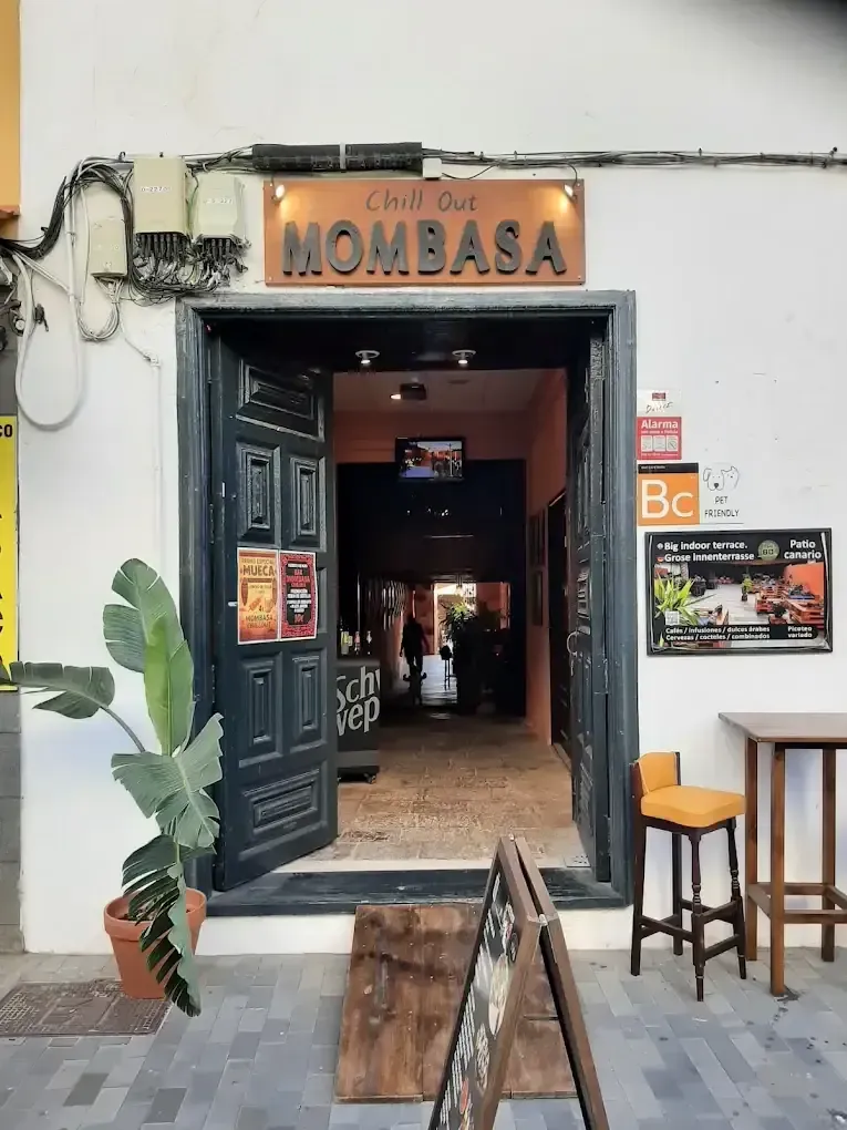Entrada al bar Mombasa con la puerta abierta, letrero en la parte superior y vista a la calle.