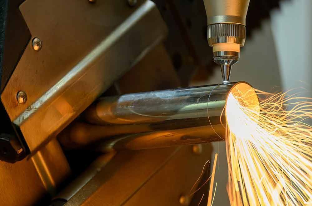 Eine Maschine schneidet ein Metallrohr, wobei Funken austreten.