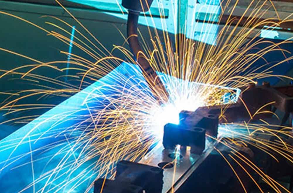 Eine Person schweißt in einer Fabrik ein Stück Metall.