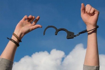 Von Handschellen befreite Hände vor blauen Himmel