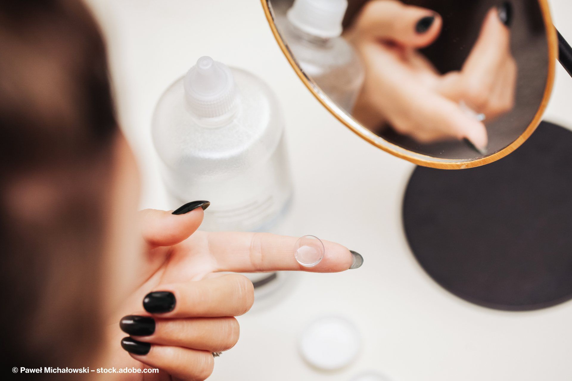 Eine Frau hält eine Kontaktlinse in der Hand.