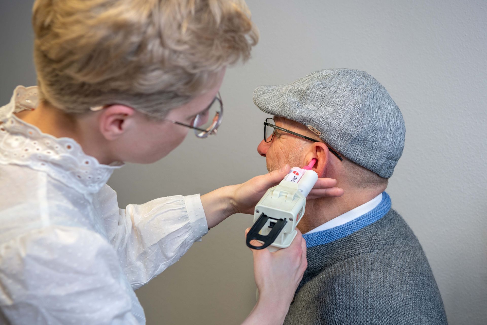 Ein Hörakustiker untersucht das Ohr eines Patienten, um den passenden Hörschutz oder ein Hörgerät auszuwählen