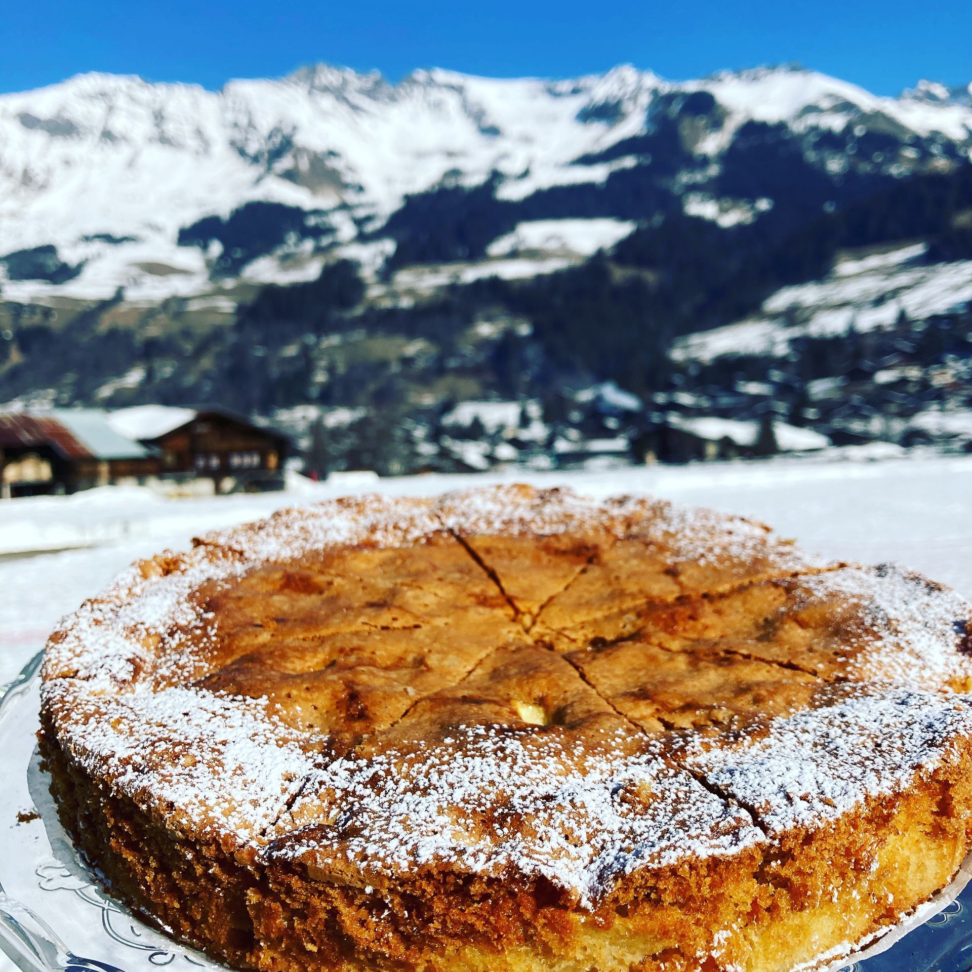 Gâteau recouvert de sucre glace sur une table enneigée avec des montagnes en arrière-plan