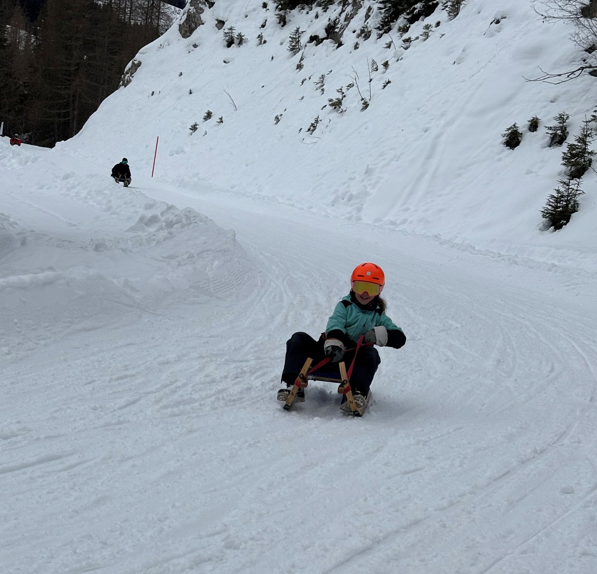Une personne descendant une pente enneigée en luge sous un ciel nuageux