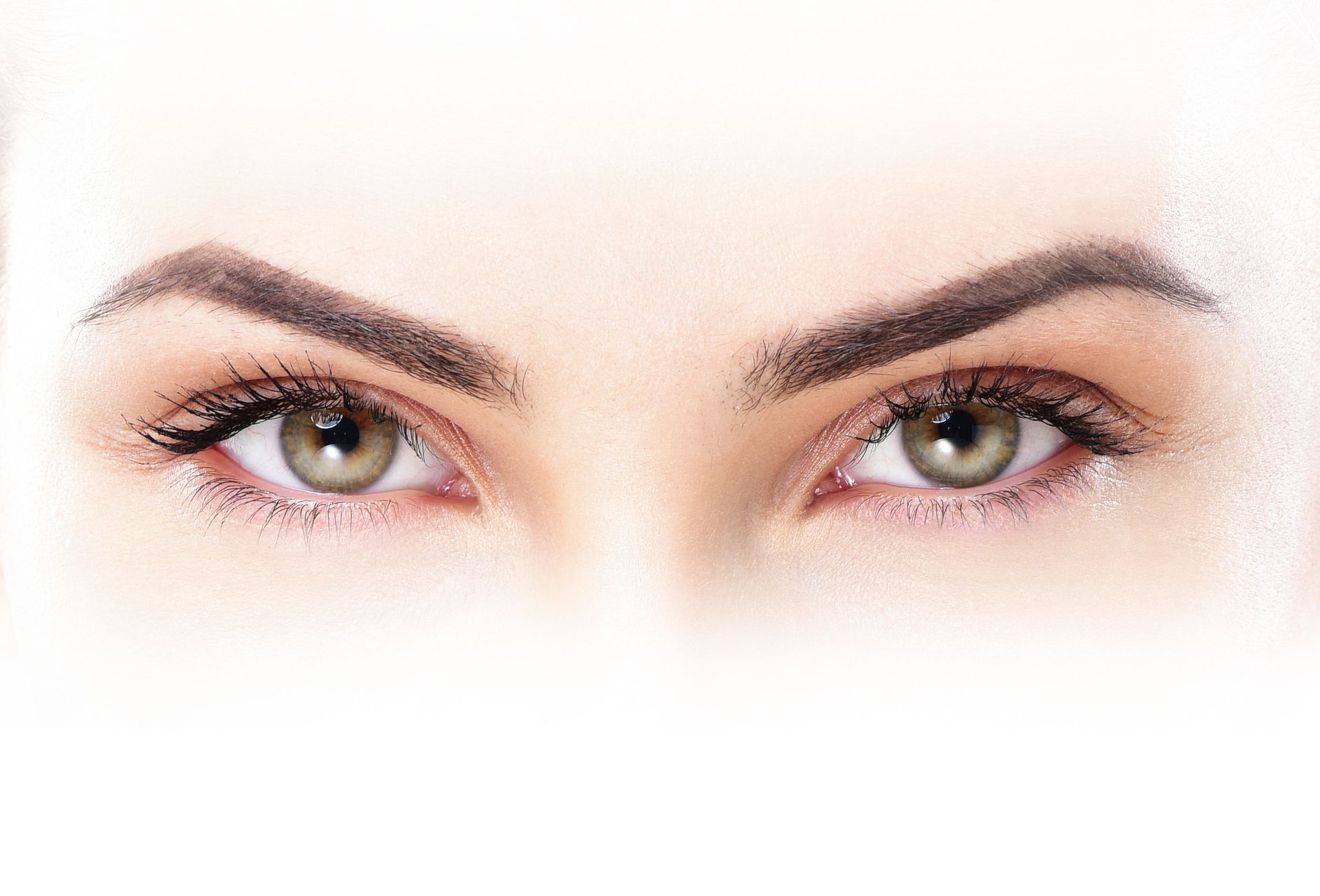 Nahaufnahme der Augen einer hellhäutigen Person. Hellgrüne Iris, dunkle Augenbrauen, leichter Blick nach oben.