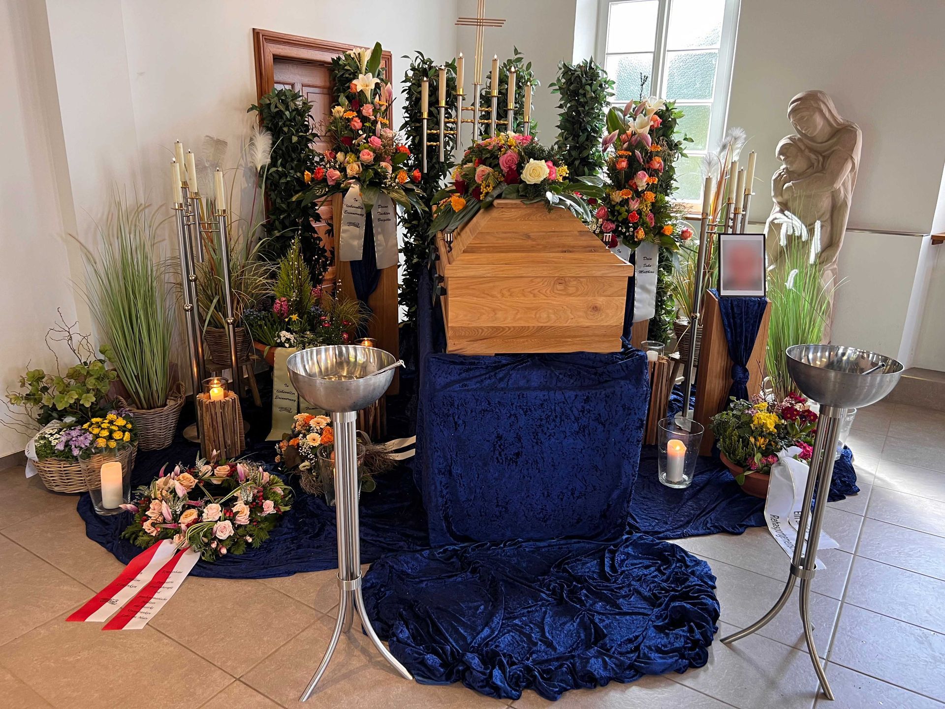 Sarg mit Blumenschmuck, Kerzen und Grabdekoration in einer Kirche