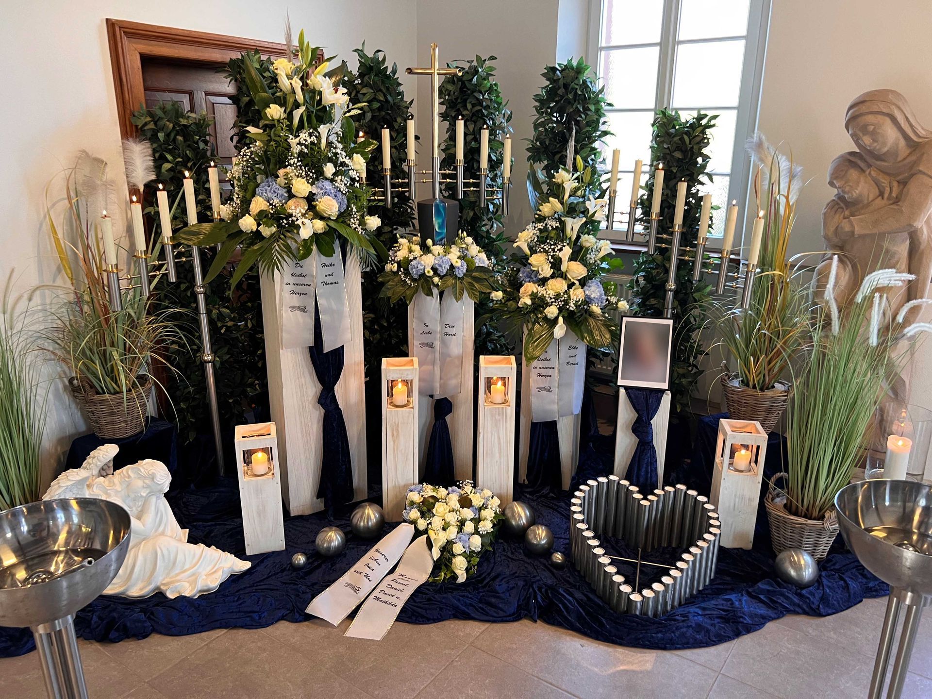 Trauerfeier mit Grabdekoration aus Blumen, Kerzen und Grablichtern in einer Kapelle