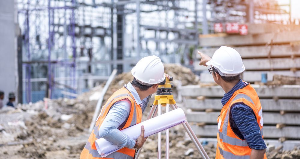Deux professionnels du BTP pointant du doigt la bâtisse en construction.