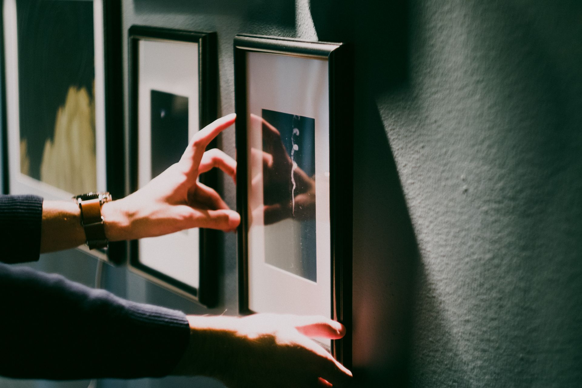 Femme plaçant des tableaux aux murs.