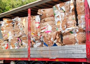 Un camión rojo transporta una gran pila de cajas de cartón.