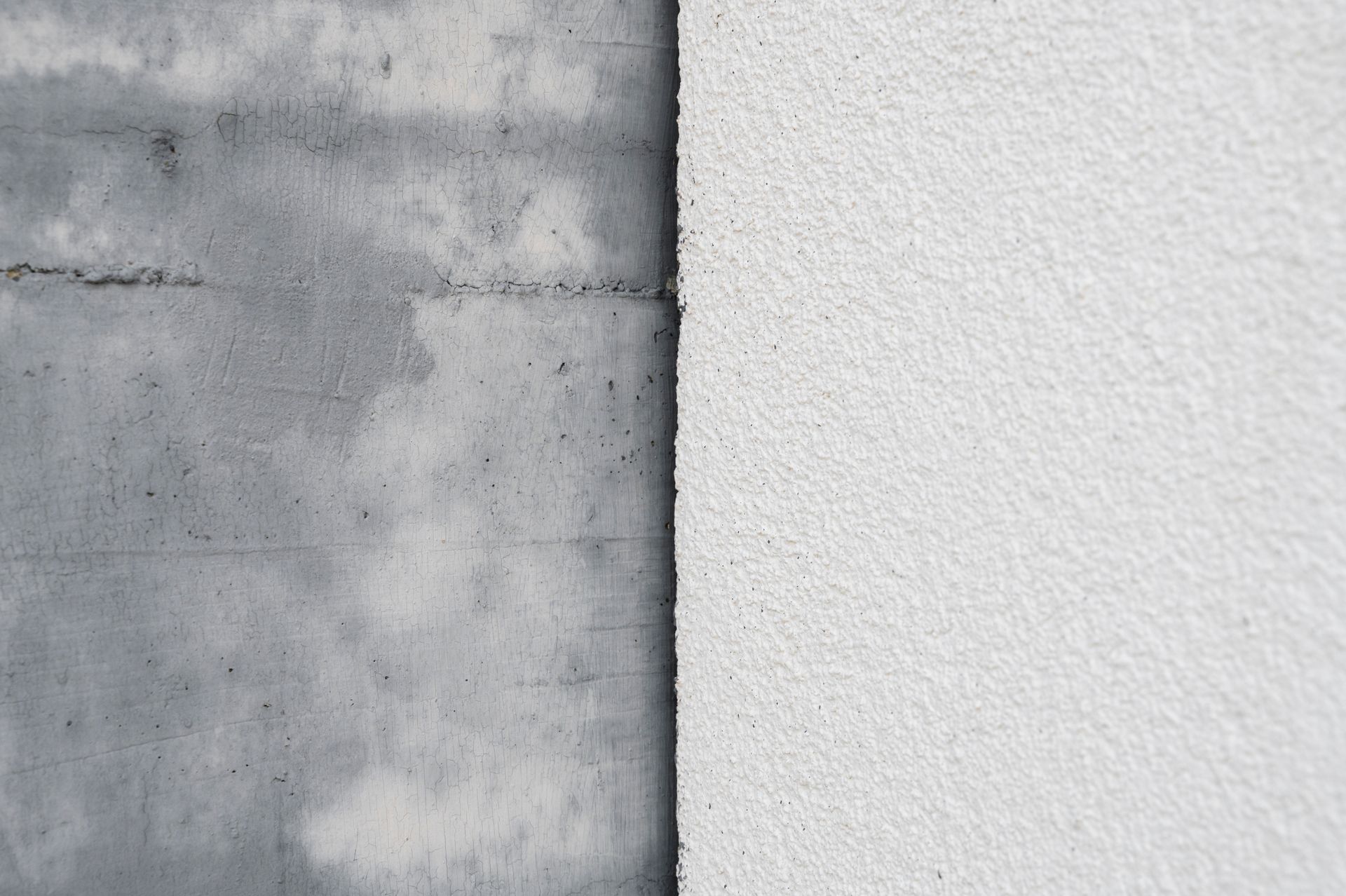 Mur en béton gris rencontrant un mur blanc texturé avec un joint vertical