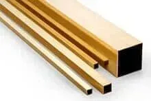 Três tubos quadrados de latão estão empilhados um sobre o outro em uma superfície branca.