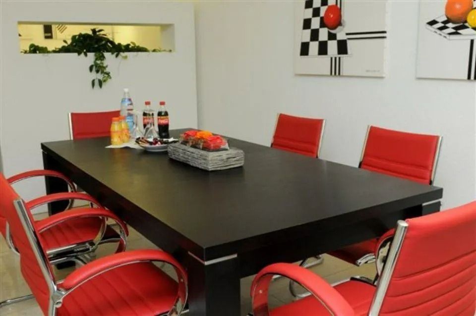 Modernes Esszimmer mit schwarzem Tisch, roten Stühlen und einem Obstarrangement als Tischdekoration