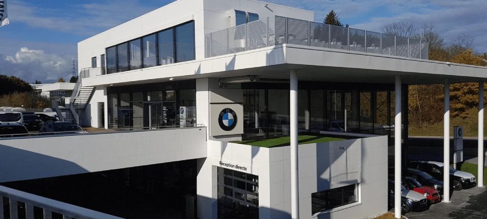 Un grand bâtiment blanc avec beaucoup de fenêtres et des voitures garées devant.