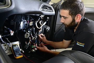 Ein Autoelektriker arbeitet an der Fahrzeugelektronik und überprüft die Kabelverbindungen