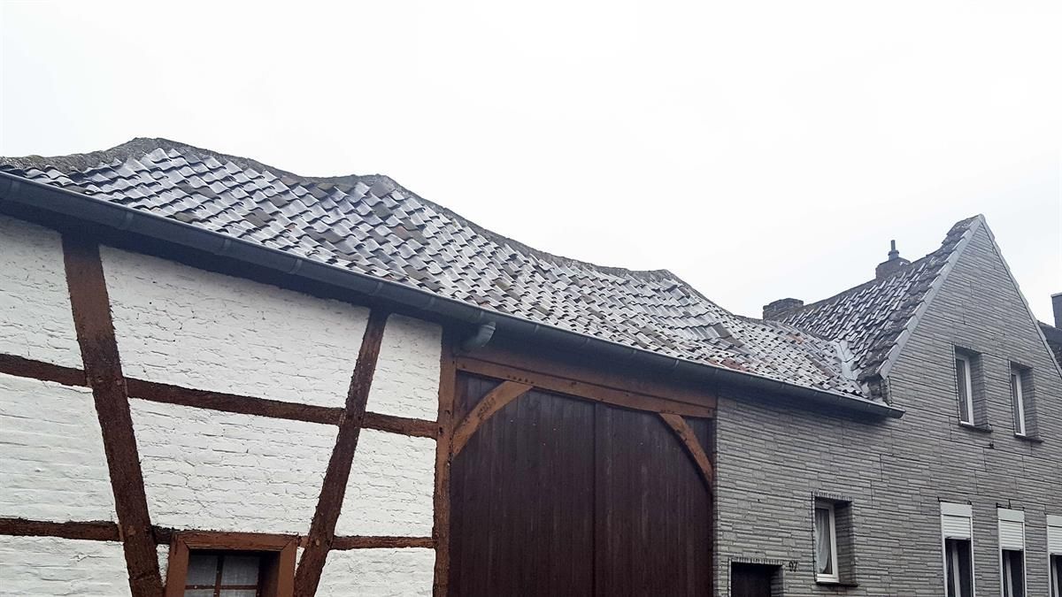 Ein Backsteingebäude mit einer Holztür und einem schneebedeckten Dach.