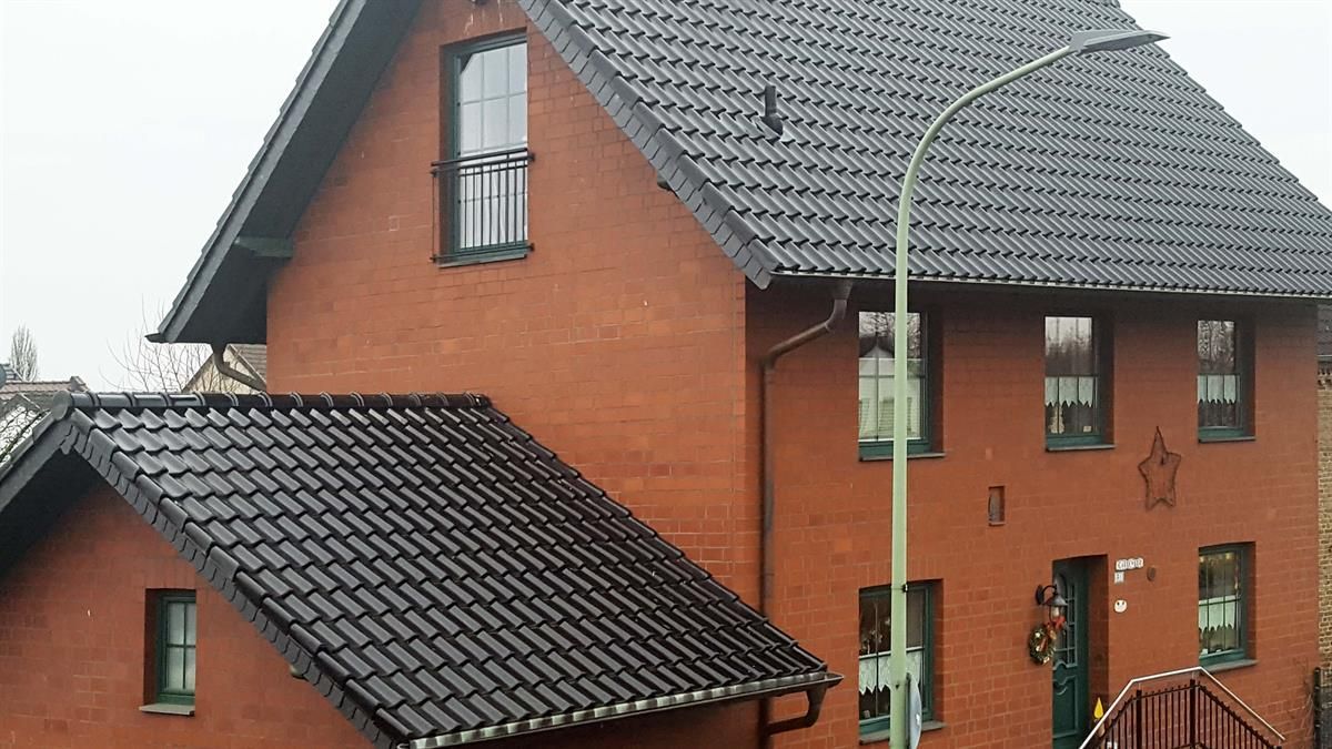 Ein rotes Backsteinhaus mit einem schwarzen Ziegeldach