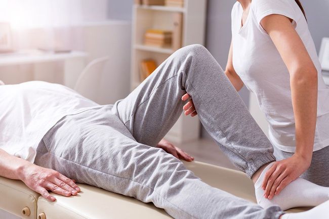 Eine Frau streckt das Bein eines Mannes auf einem Tisch aus.