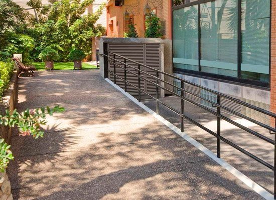 Una rampa amb barana condueix a un edifici.