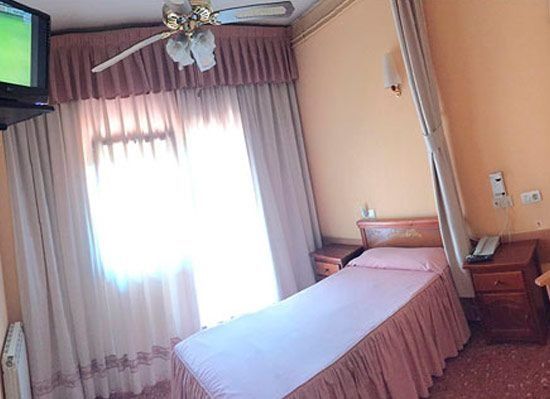 Una habitació d'hotel amb un llit individual i un televisor