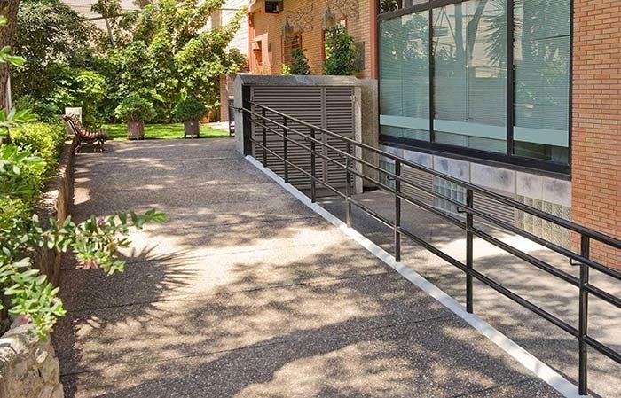 Una rampa amb barana condueix a un edifici.