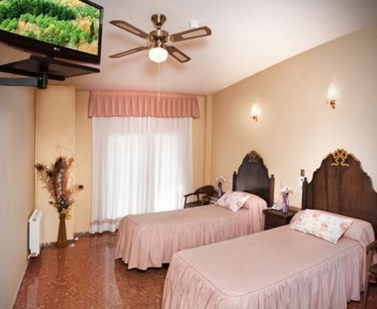 Un dormitori amb dos llits i un televisor de pantalla plana