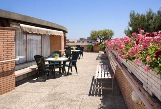 Un balcó amb taules i cadires i flors roses