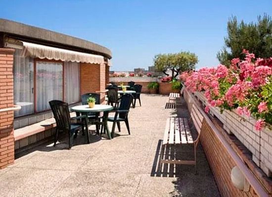 Un pati amb taules i cadires i flors roses