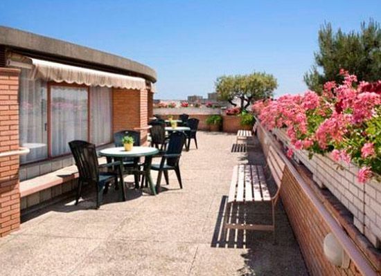 Un pati amb taules i cadires i flors roses