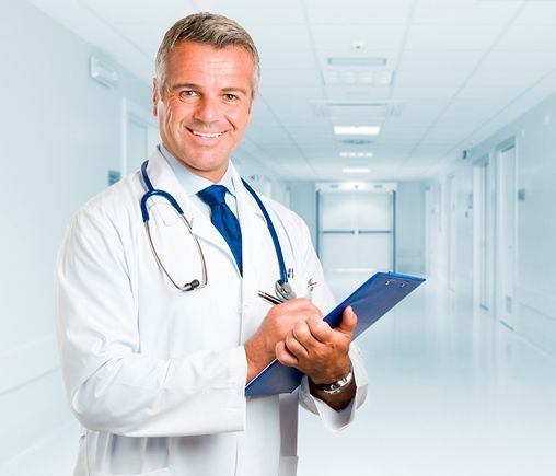 Un metge amb un estetoscopi al coll sosté un portapapers al passadís d'un hospital.