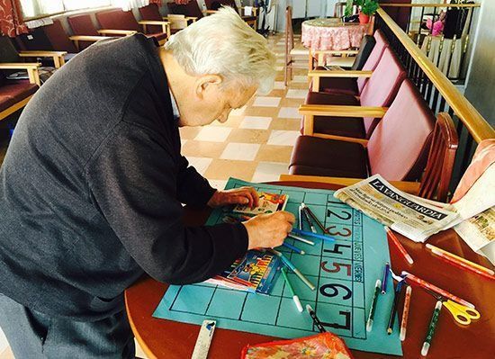 Un home seu a una taula amb un tros de paper amb números