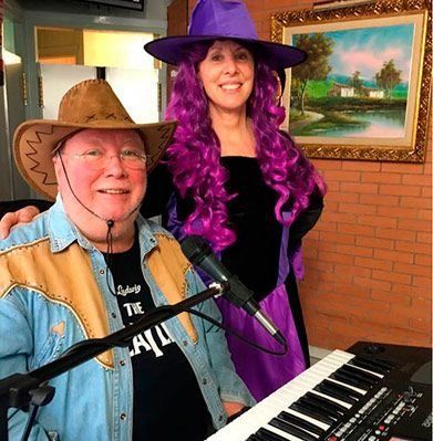 Un home amb un barret de cowboy seu al costat d'una dona amb una perruca morada