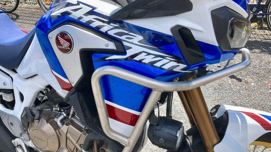 Ein blau-weiß-rotes Motorrad ist am Straßenrand geparkt.