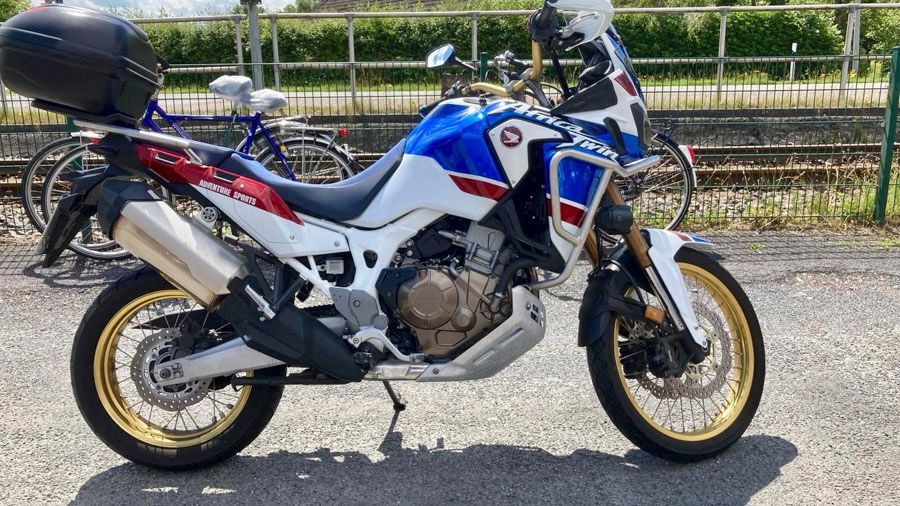 Ein blau-weiß-rotes Motorrad ist am Straßenrand geparkt.