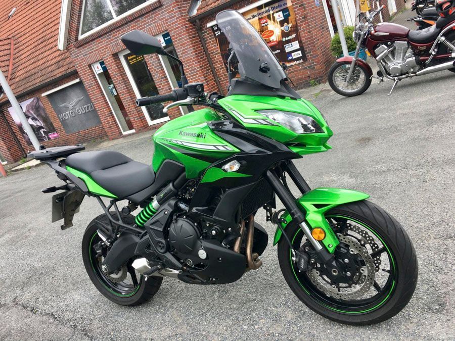 Vor einem Gebäude parkt ein grünes Motorrad.