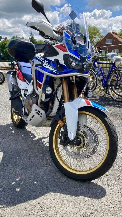 Auf einem Parkplatz steht neben Fahrrädern ein Motorrad.