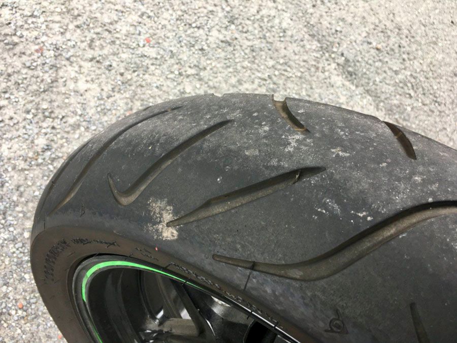 Eine Nahaufnahme eines Motorradreifens auf einer Schotterstraße.