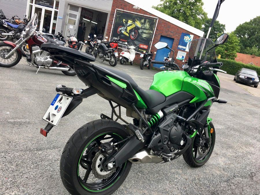 Vor einem Gebäude parkt ein grün-schwarzes Motorrad.